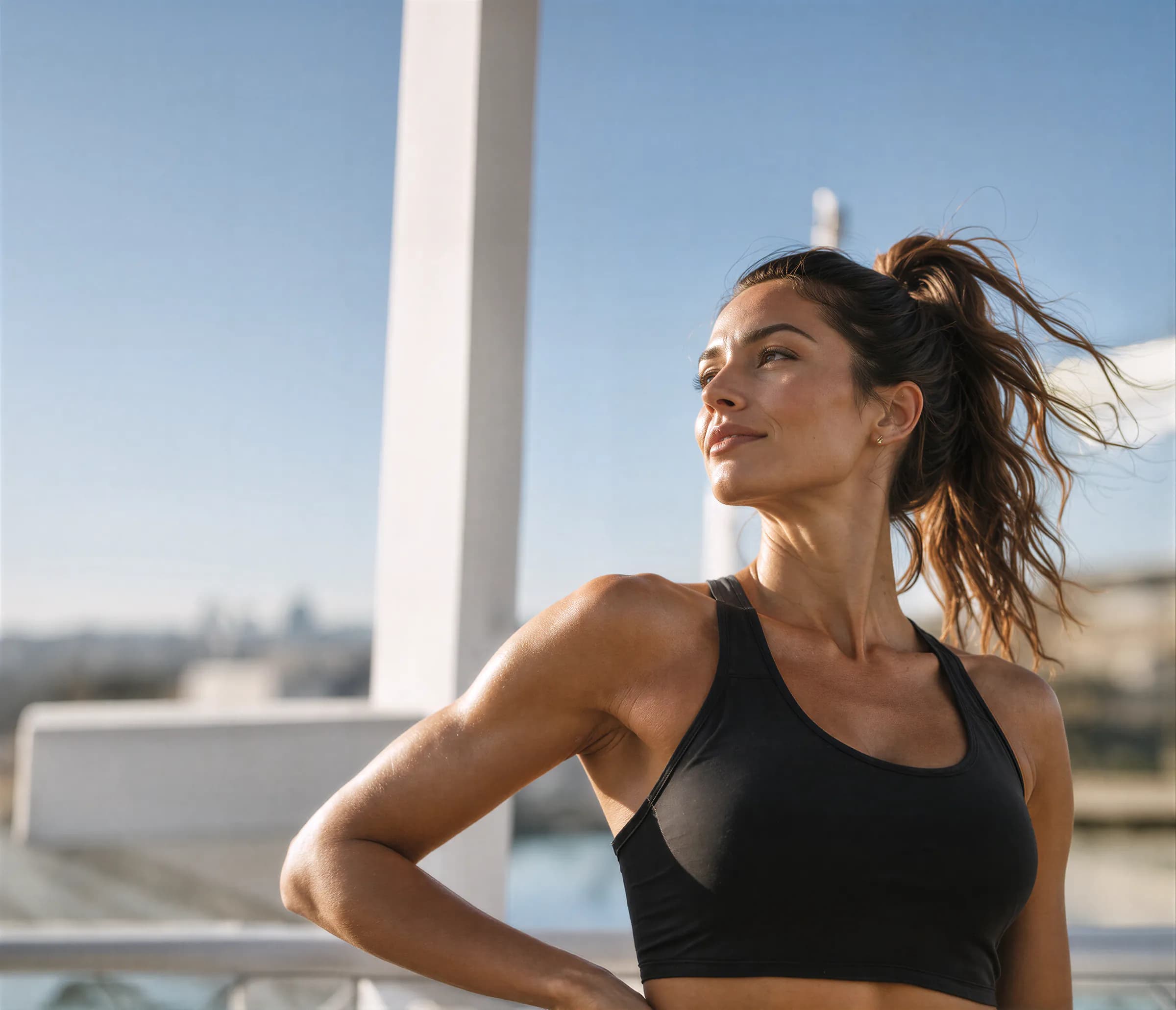 Woman in a black sports top smiling outdoors in the sun