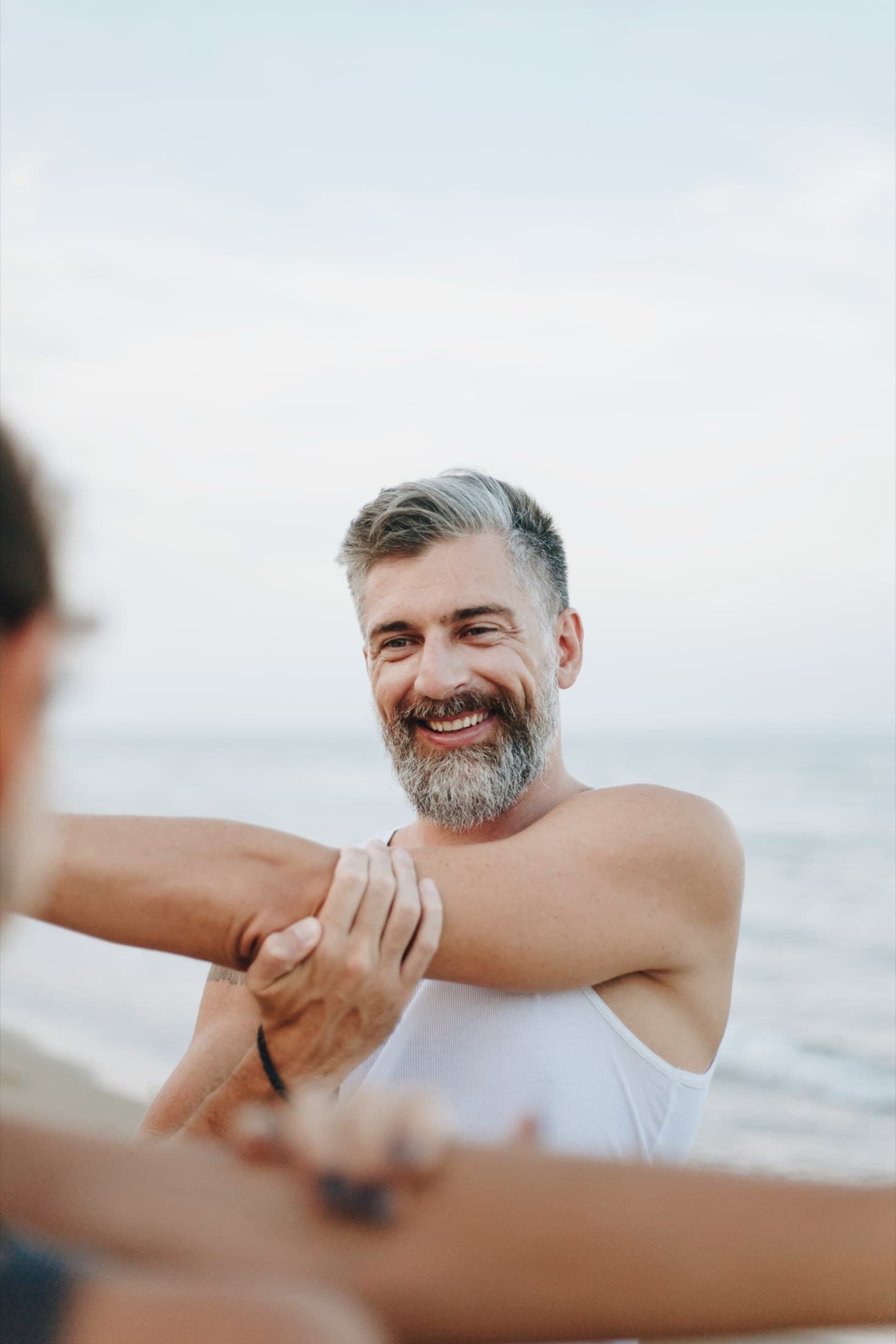 Man at the beach gripping his arm muscle