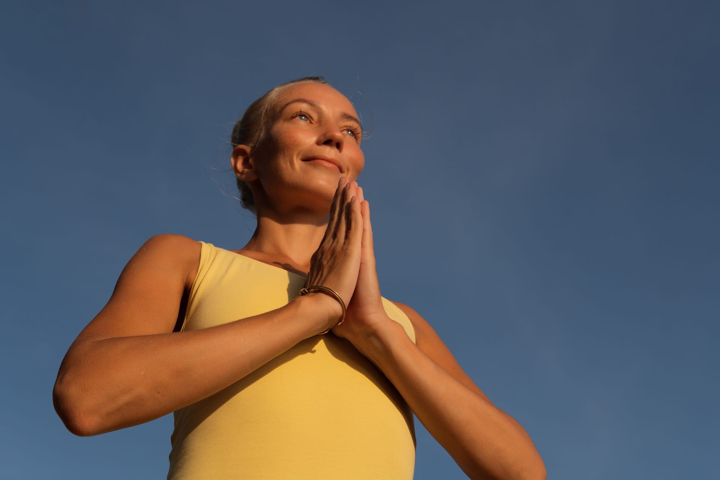 Woman meditating against a clear blue sky