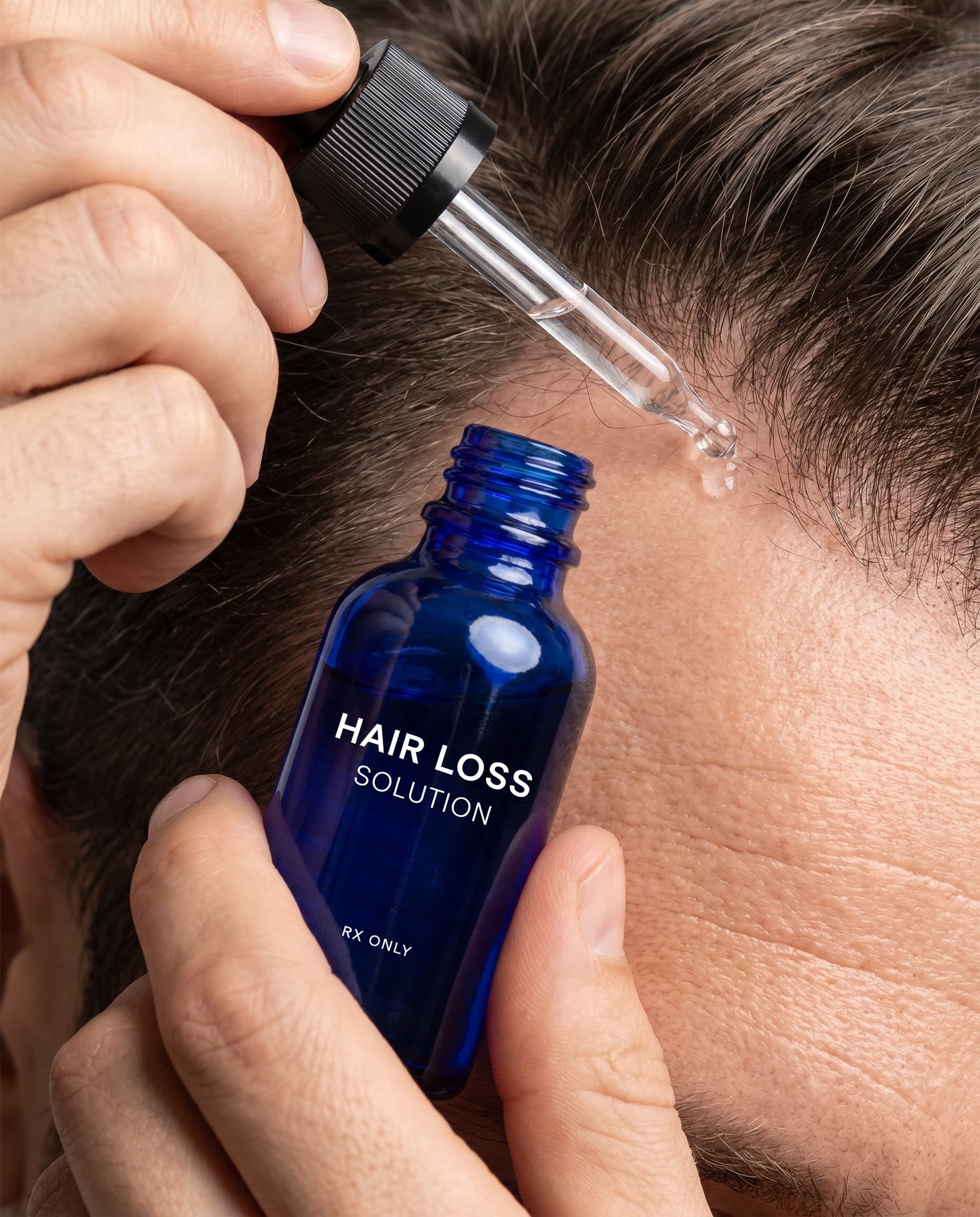 Hand applying a Hair Loss Solution dropper to a scalp