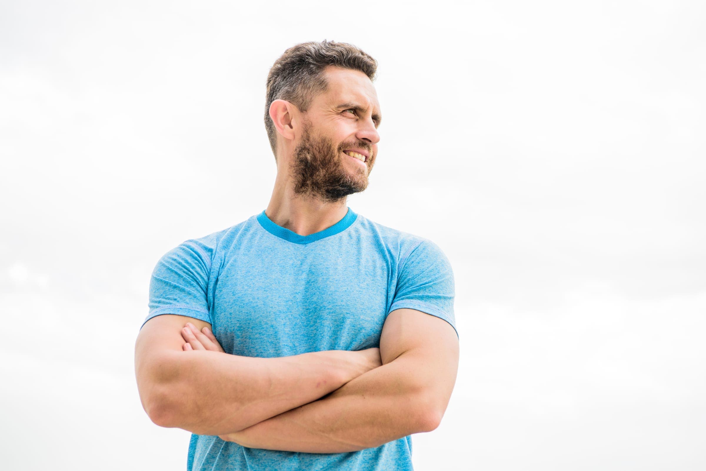 Man smiling on a clear day, arms crossed