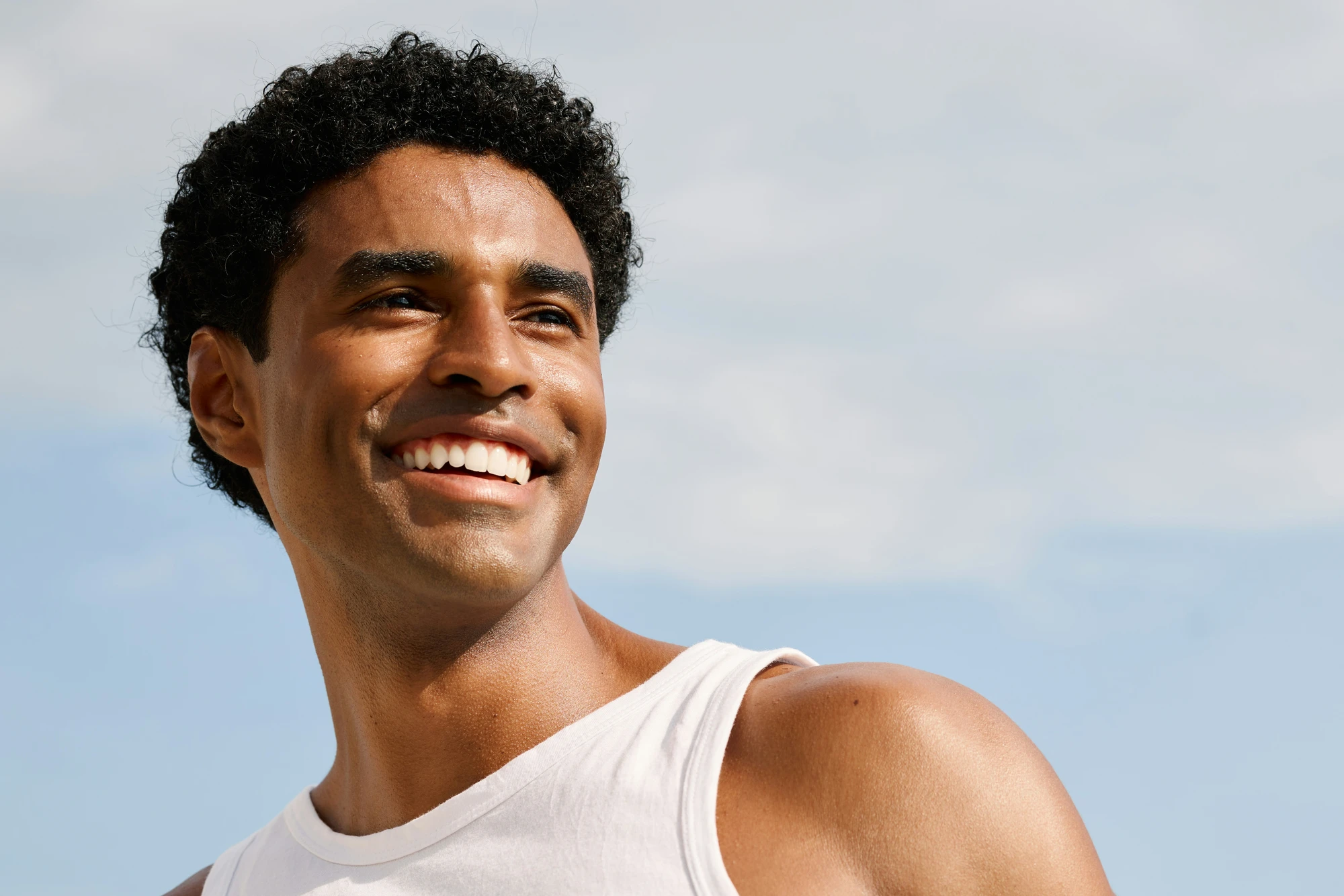 Man smiling outdoors in sunlight